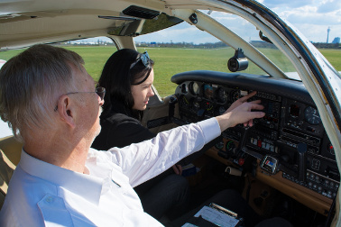 Fluglehrer zeigt Flugschülerin etwas an den Instrumenten im Cockpit eines Flugzeugs